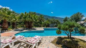 - une piscine avec 2 chaises longues à côté d'un complexe dans l'établissement Nuestra Finca Rural Orgiva by Ruralidays, à Órgiva