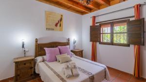 ein Schlafzimmer mit einem Bett mit lila Kissen und einem Fenster in der Unterkunft Casa La Recacha Orgiva by Ruralidays in Órgiva + 24 Fotos