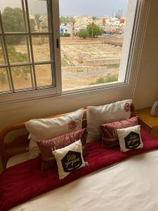 een bed met kussens voor een raam bij Larnaca Comfort Rooms in Larnaka
