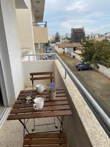 una mesa de madera en un balcón con copas y flores en Larnaca Comfort Rooms, en Lárnaca