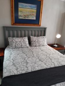 Un dormitorio con una cama y un cuadro en la pared. en Baylight Accomodation Room 2, en Mossel Bay