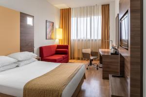 a hotel room with a bed and a desk and a chair at Ramada Encore Kyiv in Kyiv