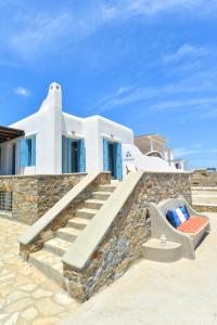 a white house with stairs and a chair at Panoramic Sea View Villa Saint Anna in Kalo Livadi