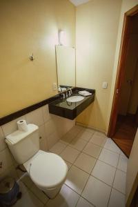a bathroom with a toilet and a sink with a mirror at Pousada Raio de Sol in Jaguarão