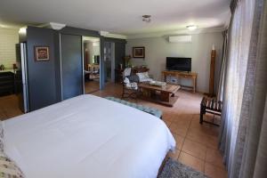 a bedroom with a white bed and a living room at 250onIndus in Pretoria
