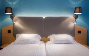 a bed with two white pillows and two lamps at Promotel in Carros