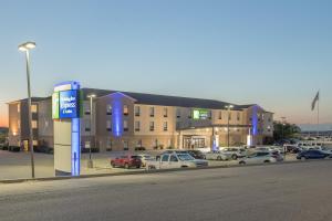 un parking avec des voitures garées devant un bâtiment dans l'établissement Holiday Inn Express & Suites N Waco Area - West, an IHG Hotel, à West