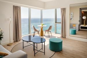 a living room with a table and chairs and windows at Arrecife Gran Hotel & Spa in Arrecife