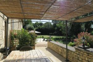 a patio with a wooden pergola and a table at Le Moulin de Charzay, éco-gîte familial en Deux-Sèvres, Nouvelle Aquitaine in Mazières-sur-Béronne
