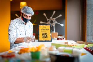 a chef wearing a face mask looking at a menu at ibis Chennai City Centre - An Accor Brand in Chennai