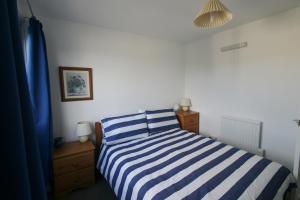 1 cama de rayas azul y blanco en un dormitorio en Freshwater Bay Holiday Cottages, en Pembroke