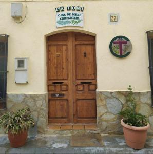 une grande porte en bois d'un bâtiment avec deux plantes en pot dans l'établissement CA TONI, à Darmós
