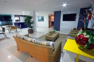 uma sala de estar com um sofá, cadeiras e uma mesa em Flat no Hotel Carneiro de Tamandaré PRAIA DOS CARNEIROS em Praia dos Carneiros