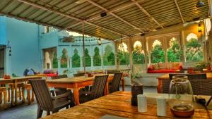 a restaurant with wooden tables and chairs and windows at Hotel Bundi House in Būndi