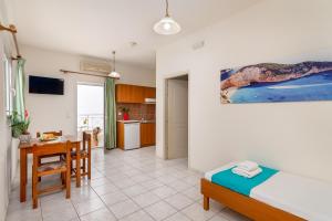 a bedroom with a bed and a table and a kitchen at Mylos Apartments Anissaras in Hersonissos