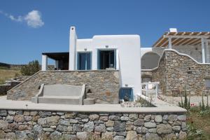 une maison blanche avec un mur en pierre dans l'établissement Panoramic Sea View Villa Saint Anna, à Kalo Livadi