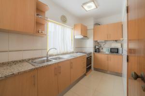 a kitchen with wooden cabinets and a sink at Atlantida by Garvetur in Quarteira