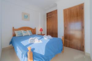 ein Schlafzimmer mit einem blauen Bett und Handtüchern darauf in der Unterkunft Atlantida by Garvetur in Quarteira