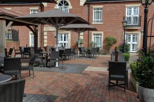 Un patio al aire libre con mesas, sillas y sombrillas. en Manor Hotel Solihull, BW Signature Collection, en Bickenhill
