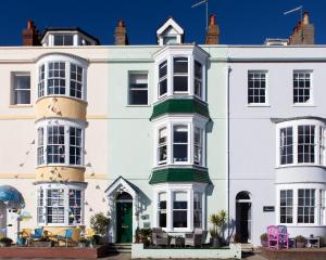uma grande casa branca com uma porta verde em Channel View Guest House em Weymouth