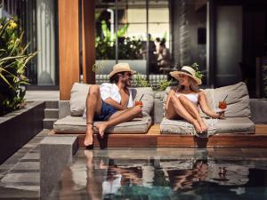 Ein Mann und eine Frau sitzen auf einer Couch neben einem Pool in der Unterkunft Contessina Suites & Spa - Adults Only in Planos