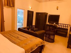 a bedroom with a bed and a chair and a television at Hotel Glitz Jaipur in Jaipur