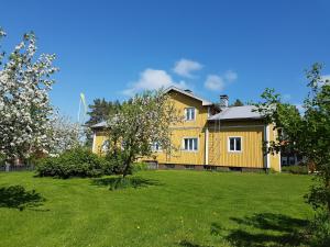 a yellow house in a yard with a green lawn at Kauppilan Matkailutalo in Ikaalinen