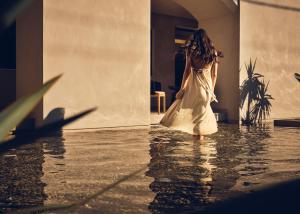 a woman in a white dress walking in the water at Contessina Hotel in Tsilivi