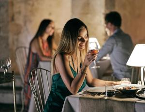 a woman sitting at a table with a glass of wine at Contessina Hotel in Tsilivi