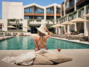 a woman in a hat sitting next to a swimming pool at Contessina Hotel in Tsilivi