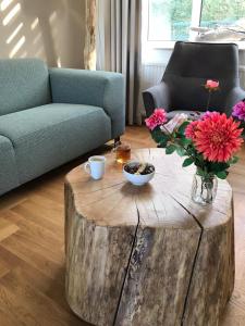 a living room with a wooden stump coffee table with flowers at Naanhover Beemden in Nuth