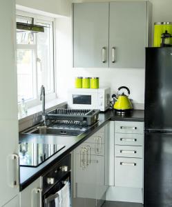 a white kitchen with a sink and a microwave at The Tushmore in Crawley