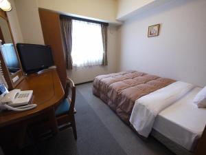 松阪市にあるホテルルートイン松阪駅東のベッド、デスク、コンピュータが備わるホテルルームです。