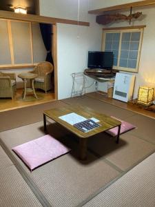 a living room with a coffee table and a television at Bamboo-Hill Sasaoka in Nozawa Onsen