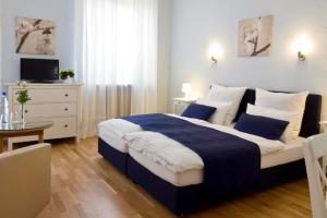 Un dormitorio con una cama azul y blanca y una mesa en Buchholz Downtown Hotel, en Colonia