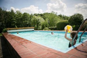 una mujer sosteniendo una pelota de voleibol en una piscina en Gutshof Schulze-Althoff, en Schöppingen