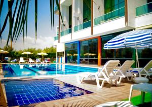 ein Schwimmbad mit Liegestühlen und Sonnenschirmen neben einem Gebäude in der Unterkunft Luna Mare Resort Mersin in Arpaçbahşiş