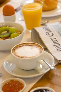 Ein Tisch mit einer Tasse Kaffee und einer Schale Obst in der Unterkunft Buchholz Downtown Hotel in Köln