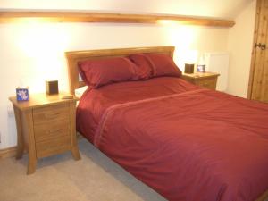 a bedroom with a red bed and two night stands at The Boathouse in Callington