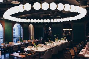 a dining room with tables and chairs and a chandelier at Kimpton Da An Taipei- an IHG Hotel in Taipei