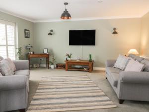 a living room with two couches and a flat screen tv at Gabby's Garden Cottage in Hull