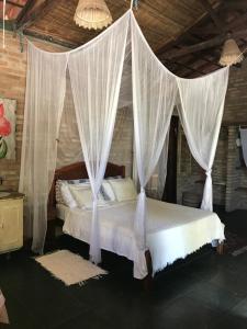 a bedroom with a canopy bed with white drapes at Refugio Mar Aberto in Alcobaça