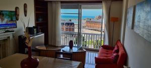 - un salon avec une chaise rouge et une grande fenêtre dans l'établissement ArielMardel, à Mar del Plata