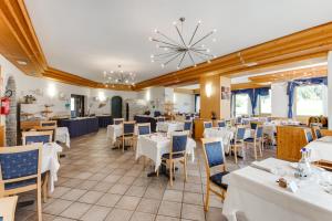 una sala da pranzo con tavoli e sedie bianchi di Hotel Bellamonte a Predazzo