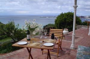 a wooden table with plates and wine glasses on a patio at Cottons Cottages in Simonʼs Town