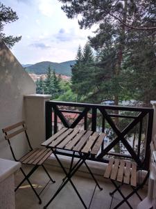 a bench and two chairs on a balcony with a view at Bendida Apartments in Velingrad