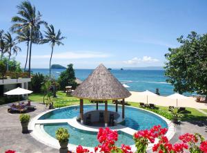 a resort swimming pool with a gazebo and the ocean at Orlowsky Discovery Candidasa Hotel in Candidasa