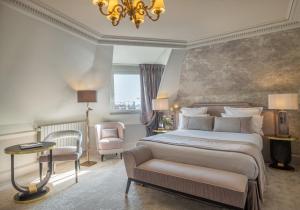 a bedroom with a bed and a chair and a chandelier at Hôtel Elysia in Paris