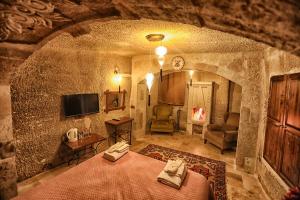 a room with a bed and a tv in a stone wall at The Dorm Cave By Travellers in Goreme