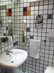 a white tiled bathroom with a sink and a phone at Gaia B&B in Castrovillari